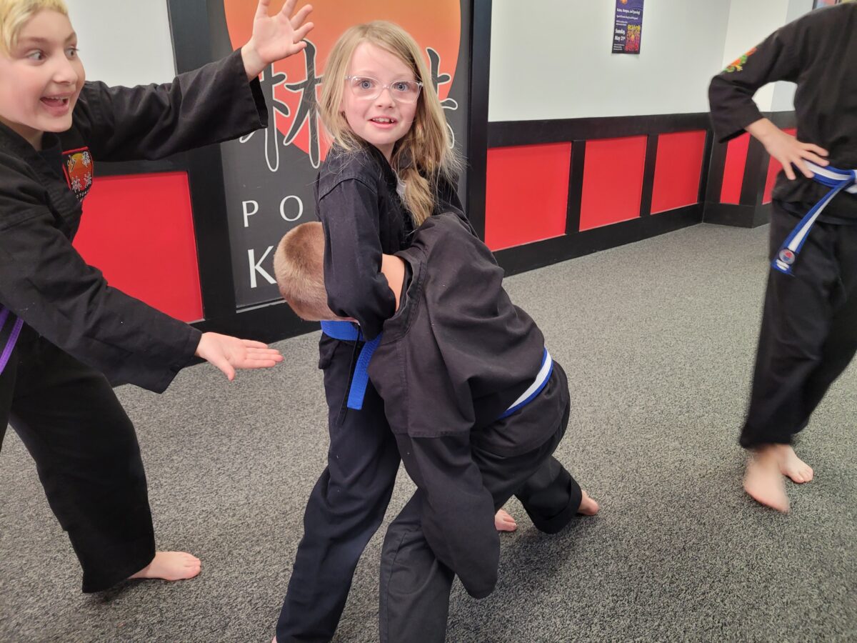 Martial Arts for Kids 3 One child holds another child in a side choke as a third presents them with joy
