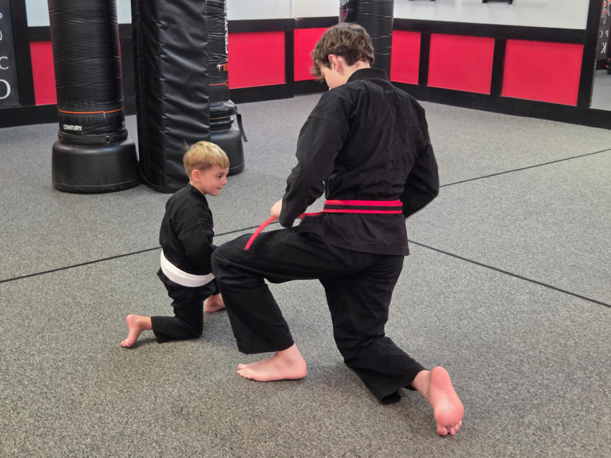 Martial Arts for Kids 4 A young instructor teaches a young child how to tie his white belt